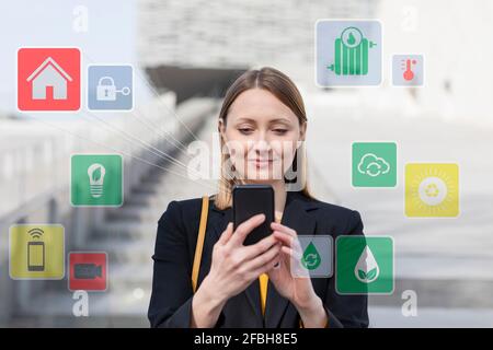 Female entrepreneur using mobile phone while standing by icon set outdoors Stock Photo