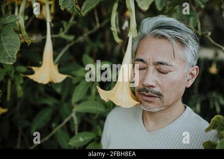 Mature man looking over shoulder while standing in garden Stock Photo