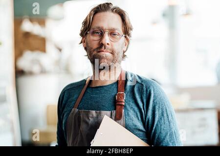 Mature male owner with clipboard at coffee shop Stock Photo