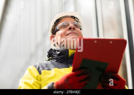 Male entrepreneur looking away while holding clipboard Stock Photo