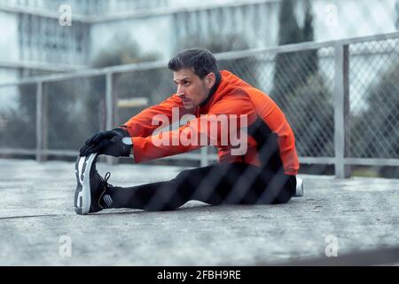 Athletic man doing stretching exercise in park Stock Photo