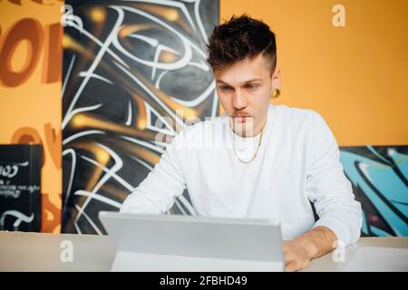 Young hipster man working while using laptop in studio Stock Photo