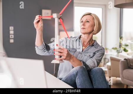 Thoughtful female professional examining wind turbine model at home office Stock Photo