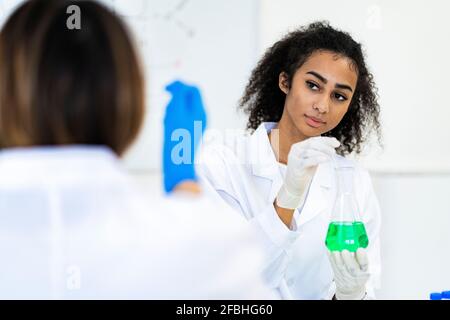Female researcher looking at coworker while working in laboratory Stock Photo