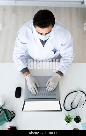 Male medical expert using laptop in hospital during COVID-19 Stock Photo