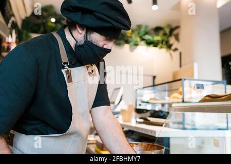Mature man working in restaurant kitchen during COVID-19 Stock Photo
