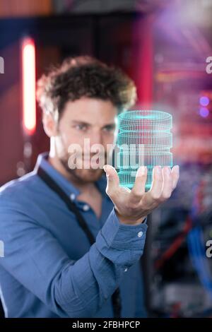 Male IT professional holding hologram of database in server room Stock Photo