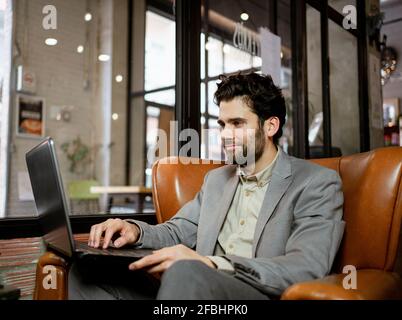 Smiling male entrepreneur working on laptop in cafe Stock Photo
