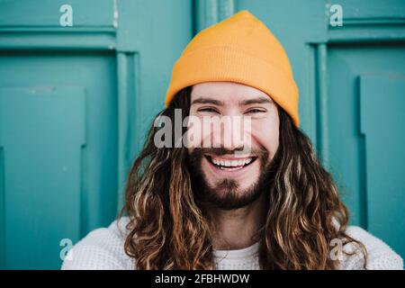 Cheerful male hipster wearing knit hat in front of door Stock Photo