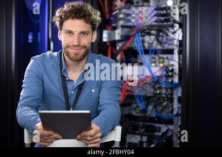 Male IT engineer with digital tablet sitting on chair in server room Stock Photo