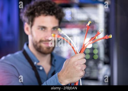 Male IT engineer holding patch cord cables in server room Stock Photo