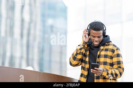 Man wearing headphones while using smart phone Stock Photo