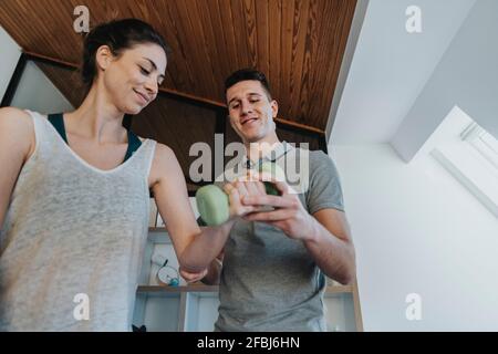 Male physiotherapist guiding female patient in exercising with dumbbell in medical practice Stock Photo