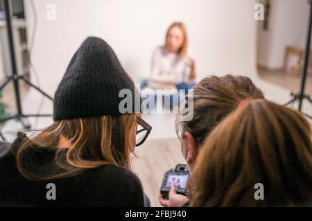 Photographer sharing camera with female coworker in studio Stock Photo