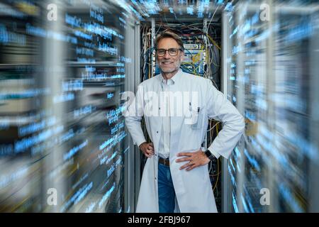 Server technician wearing lab coat standing amidst algorithms at data center Stock Photo