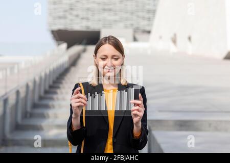 Smiling mid adult businesswoman using futuristic digital tablet outdoors Stock Photo