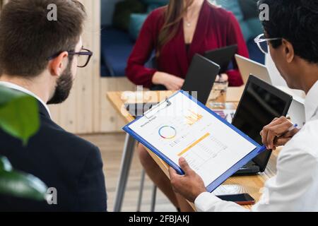 Colleagues brainstorming over business plan on clipboard in meeting at office Stock Photo
