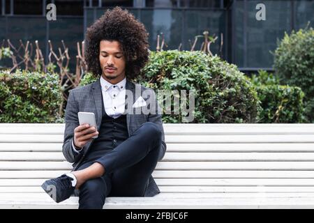 Handsome young businessman using mobile phone on bench Stock Photo