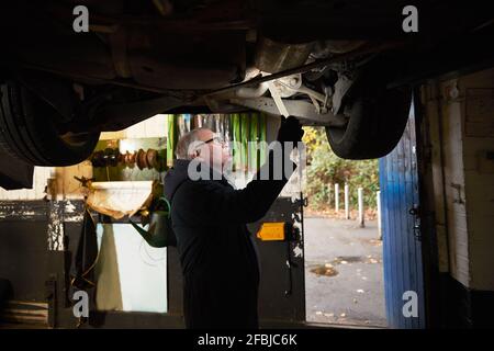 Senior male auto mechanic examining car in workshop Stock Photo
