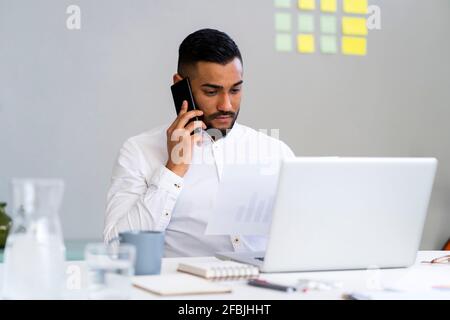Serious businessman looking at strategy while talking on smart phone at office Stock Photo