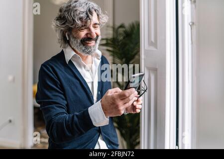 Smiling handsome man using smart phone at home Stock Photo