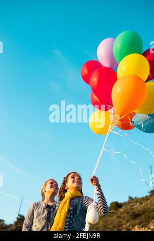 Cheerful girls playing with colorful helium balloons Stock Photo