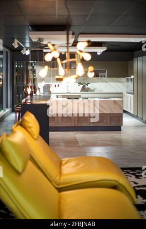 View to modern open plan kitchen with yellow leather chairs in the foreground Stock Photo