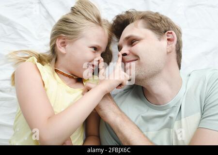 Father reading book with daughter and son in bed Stock Photo