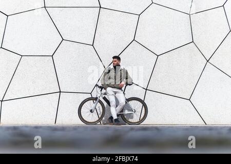 Young man leaning on bicycle while looking away Stock Photo
