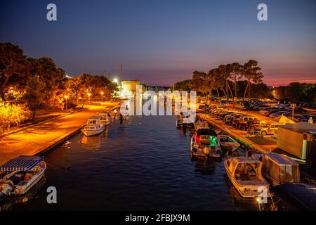Croatia, Split-Dalmatia County, Trogir, Motorboats moored along illuminated city canal at night Stock Photo