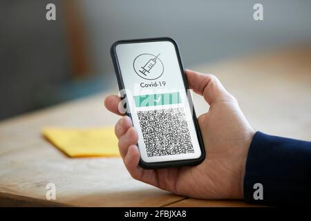 Man holding smart phone with COVID-19 vaccination QR code Stock Photo