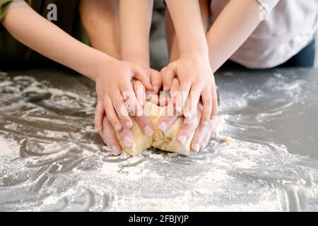 Father and children kneading dough together on kitchen island Stock Photo