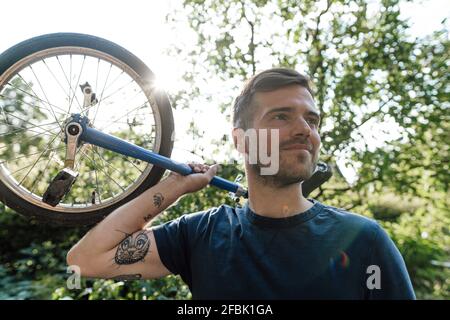 Man with unicycle looking away during sunny day Stock Photo