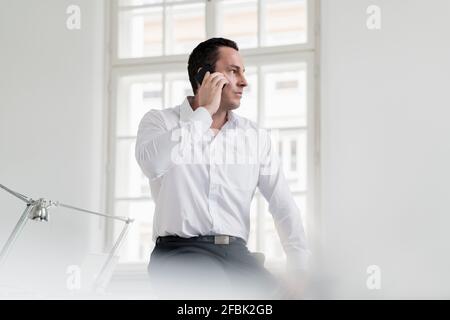 Male entrepreneur talking on phone at workplace Stock Photo