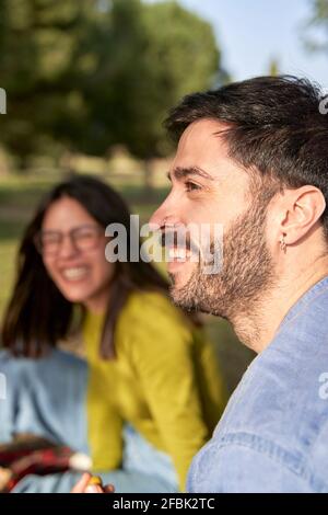 Smiling hipster man looking away while enjoying picnic with girlfriend Stock Photo