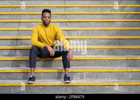 Relaxed man sitting on yellow staircase Stock Photo