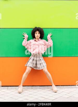 Young woman leaning on multi colored wall Stock Photo
