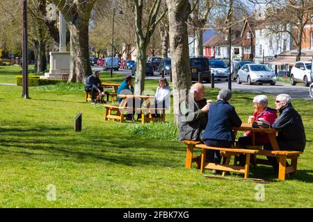 People sitting outside on benches placed along the high street, tenterden, kent, uk Stock Photo