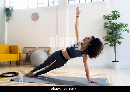 Young woman practicing side plank pose in living room Stock Photo
