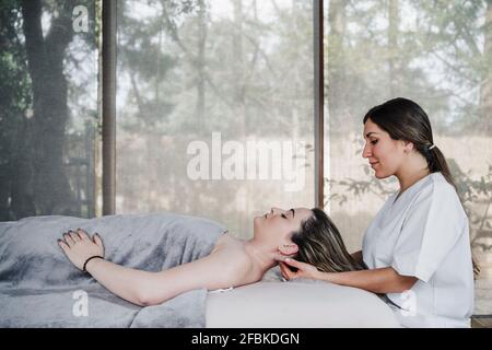 Female physical therapist head massaging patient in clinic Stock Photo