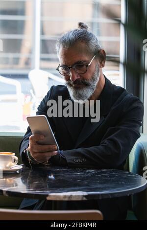 Businessman using mobile phone while sitting at cafe Stock Photo