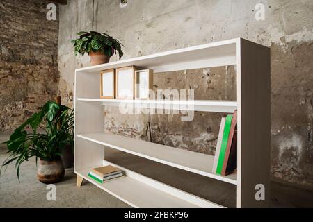 Few books and picture frames on mostly empty wooden bookshelf Stock Photo