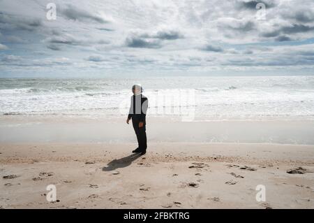 Astronautic man wearing space helmet while standing on sea shore Stock Photo