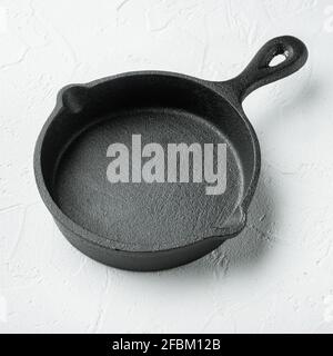 Kitchenware frying, cast iron pan, on white stone surface, square format Stock Photo