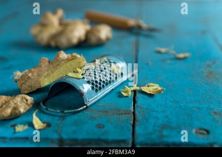 Ginger root and grater lying on blue wooden surface Stock Photo