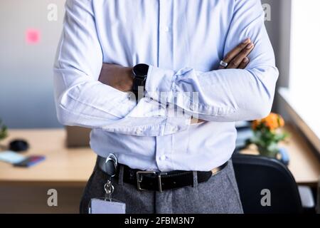 Man with arms crossed standing in office Stock Photo