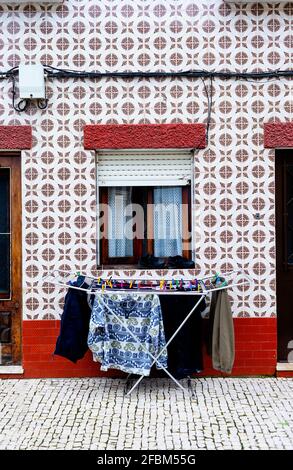 Laundry drying on drying rack standing in front of mosaic wall with square tiles Stock Photo