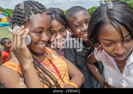 Miami Florida,Tropical Park Drug Free Youth In Town DFYIT,teen student anti addiction group picnic,Black teens using smartphone mobile cell phone phon Stock Photo