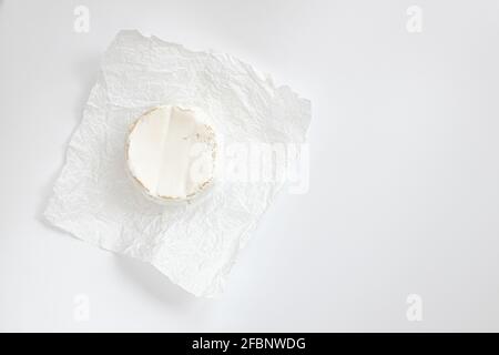 cheese camembert or brie on white background, cheese on white parchment paper, head of tasty camembert or brie cheese, french cheese, top view Stock Photo