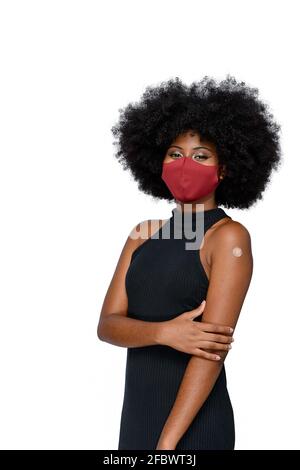 black teenager wearing protective mask against covid-19 with a smile on his face shows the vaccine brand, isolated on white background Stock Photo